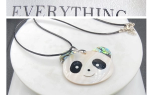 Détail macro du pendentif panda géant incrusté de nacre et de coquille d'abalone