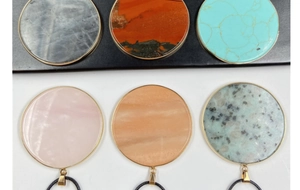 Detailed close-up of colorful round natural stone pendants with gold-plated edges