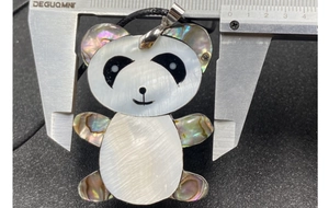 Mesure de la largeur du pendentif panda en nacre et abalone avec un pied à coulisse