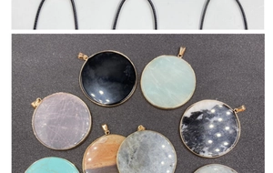 Flat lay of multiple round natural stone pendants with gold metal edges and black cords