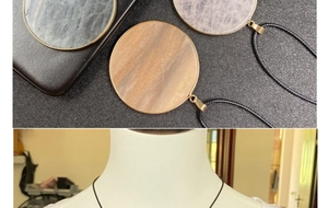 Macro detail of round natural stone pendants with gold metal edging and black cord straps