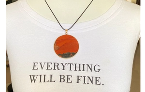 Detail of a natural red jasper disc pendant with black cord on a model neck
