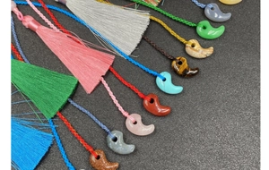 Flachbild von bunten Magatama-Quasten mit gewebten Kordeln und diversen Edelsteinanhängern