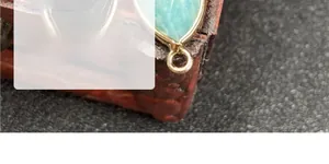 Macro shot of faceted teardrop amazonite pendant with gold plated bezel on a vintage box
