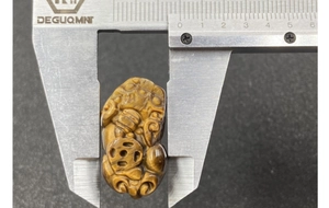 Makroaufnahme eines Tigerauge-Anhängers bei Messung der 20mm Breite mit Messschieber