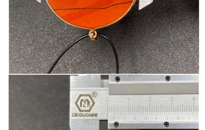 Detail view of a 40mm round red jasper pendant measured with a caliper on grey background