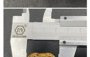 Detaillierte Messung der Breite des Tigerauge-Anhängers mit einem Messschieber (ca. 2,5 cm)