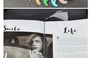 Detailansicht eines blauen Quasten-Lesezeichens mit Kordel und Perle auf einem Magazin
