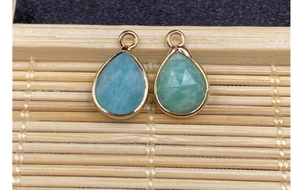 Detailed view of faceted water-drop light blue stone pendants with gold metal edge