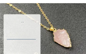 Détail macro du pendentif flèche en quartz rose avec bordure plaquée or sur chaîne dorée