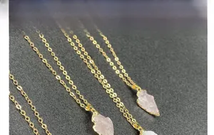 Gros plan de pendentifs en quartz rose en forme de flèche avec bords dorés sur chaînes