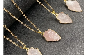 Détail de quatre colliers flèches en quartz rose avec bords plaqués or sur fond noir mat