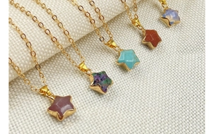 Close-up of gold-rimmed star-shaped gemstone pendants on thin gold chains