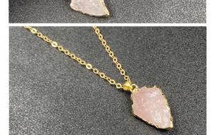 Détail macro du pendentif en quartz rose en forme de flèche avec bords dorés sur noir