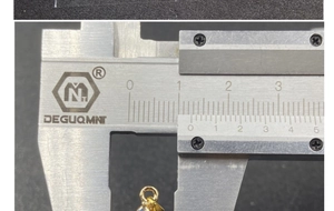 Detail view of gold star pendant size measurement showing 10mm diameter on a caliper