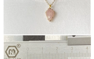 Détail d'un pendentif flèche en cristal rose doré mesuré avec un pied à coulisse