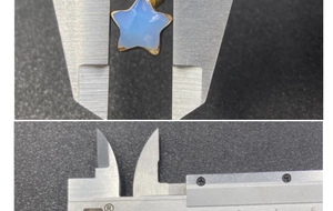 Measuring light blue star pendant width using calipers on a grey textured background