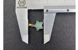 Macro shot measuring a gold-edged green jade star pendant with a digital caliper
