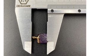Macro shot showing 12mm width measurement of faceted amethyst pendant with gold loop