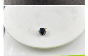 Macro detail of geometric black multi-faceted stone pendant with polished gold clasp