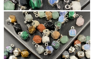 Close-up of assorted hexagonal stone pendants with silver metal caps for jewelry making