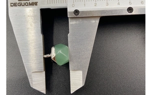 Detail showing 10mm light green faceted gemstone pendant being measured with a caliper