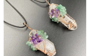 Détail d'un pendentif arbre de vie en cristal blanc entouré de fil de cuivre et gemmes