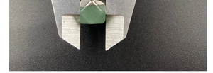 Measuring a green faceted square crystal pendant with a caliper for precise dimensions
