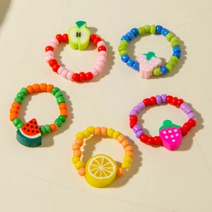 Detailed view of five colorful beaded rings with various clay fruit charms