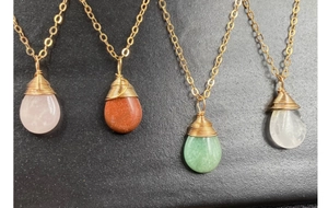 Detalle de cuatro colgantes de cristal en forma de gota con alambre dorado en fondo gris