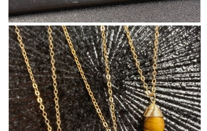 Primer plano de colgante de ojo de tigre en gota con alambre dorado y cadena fina