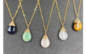 Detalle de cinco collares de cristal en forma de gota con envoltura de alambre dorado