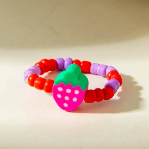 Close-up of a beaded strawberry ring featuring red and purple resin beads and a cute pendant