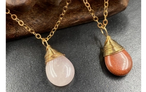 Detalle de colgantes de cuarzo rosa y piedra de sol envueltos en alambre con cadena dorada