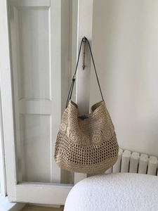 Detail of hollow hand-woven straw beach bag with delicate wavy patterns and leather strap