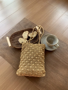 Macro view of detailed hollow woven pattern on straw shoulder bag on a table