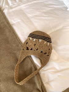 Vue détaillée du motif floral ajouré complexe sur ce sac cabas en paille tissée main