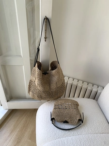 Detail of handmade khaki woven straw beach bag set with black leather straps and button