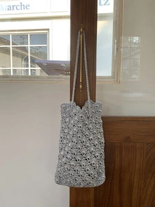Detail of silver hand-woven shoulder bag with intricate shell-patterned crochet texture