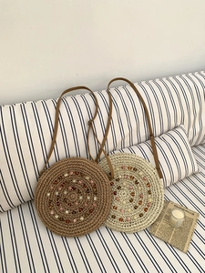 Detail of round straw bags in brown and beige with colorful beads and leather straps