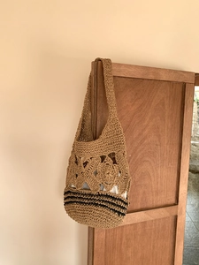 Détail du sac cabas en paille crocheté à la main avec motifs de fleurs ajourés et rayures