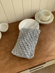 Detail of silver crochet shoulder bag with intricate scallop hollow pattern and metallic finish