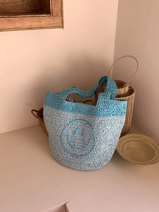 Detailed texture of blue crochet handbag featuring a large knitted smiley face pattern