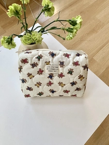 Détail d'une trousse de maquillage matelassée blanche avec motifs d'ours et fermeture