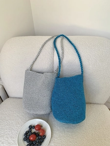 Gros plan de sacs seaux tissés à la main en argent et bleu sur un canapé blanc
