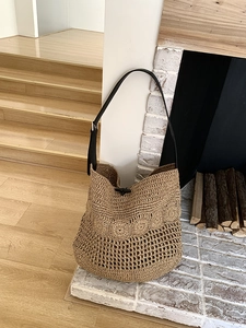 Detail of bohemian straw shoulder bag featuring hollow crochet pattern and horn buckle closure