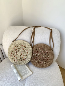 Detail of round straw bag with colorful spiral beadwork on a white textured sofa