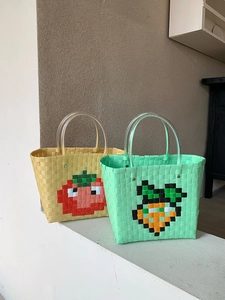 Detail of hand-woven plastic beach bags with pixelated tomato and carrot patterns