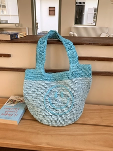 Detail of blue crochet tote bag showing handmade knit texture and smile pattern