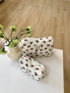 Détails de deux trousses de maquillage matelassées crème avec motifs ours en deux tailles